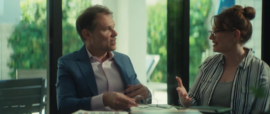 A businessman and businesswoman finalize their meeting with a handshake, smiling after a successful collaboration in a modern office