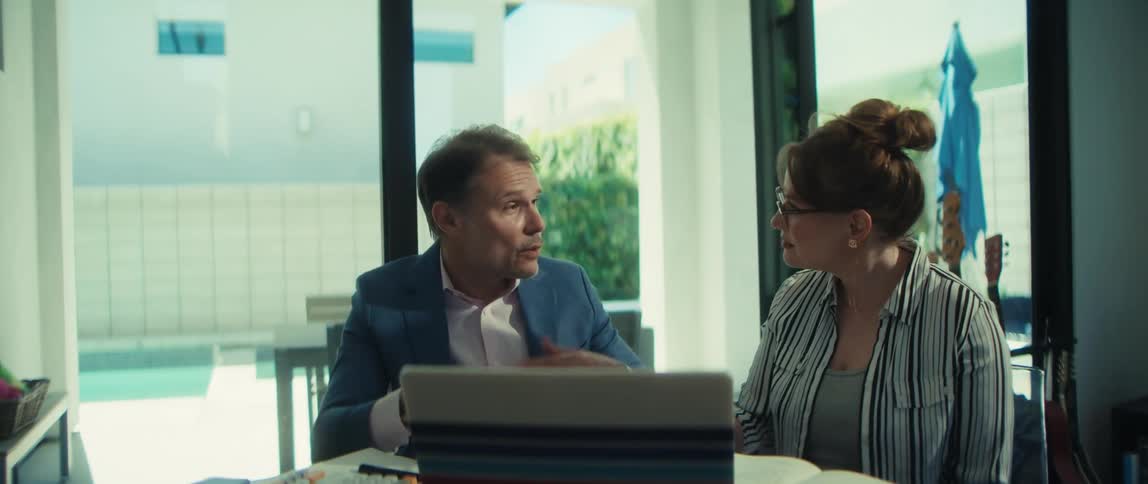 A man and woman happily shake hands to seal a business deal during a collaborative meeting in a bright, modern space