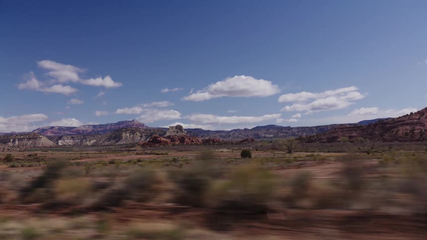A side-view driving plate captures the sprawling desert and colorful mountain ranges of the American Southwest on a sunny day