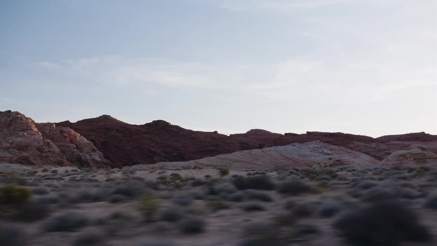 Passing by the unique red and white sandstone hills of a desert park at sunrise