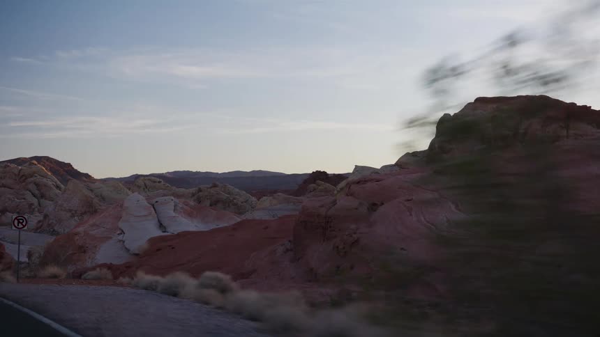 A scenic driving shot slowly reveals the iconic colorful red and white sandstone formations of the Valley of Fire at sunset