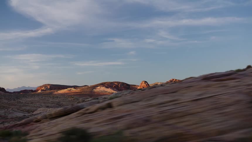 A scenic drive through a majestic desert landscape with vibrant red and white rock formations glowing in the warm light of sunset
