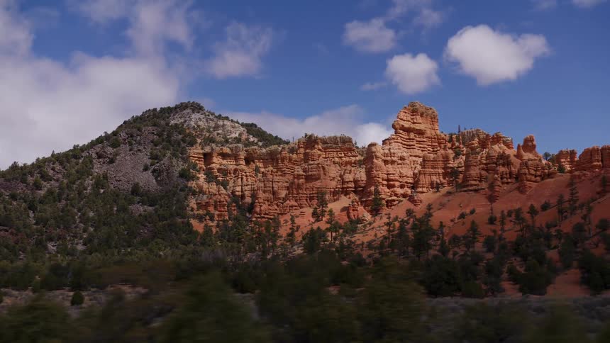 A scenic drive reveals the stunning red rock canyons and hoodoos of the American Southwest under a partly cloudy sky