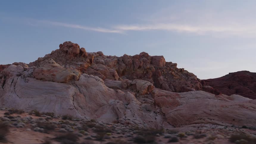 Driving past stunning multicolored rock formations in a desert landscape at dusk
