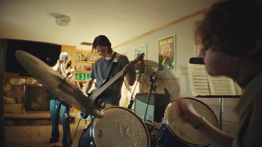 Dynamic shot revealing a young rock band energetically practicing together in their home music room