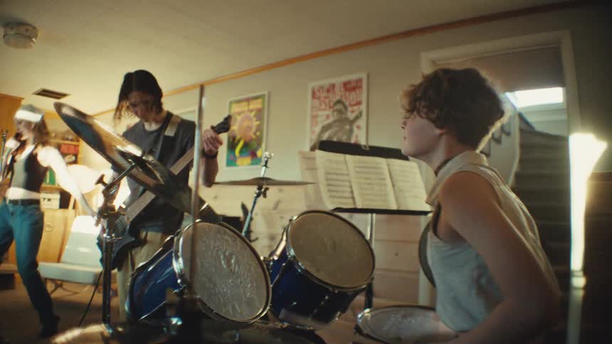 Dynamic shot revealing a young rock band energetically practicing together in their home music room
