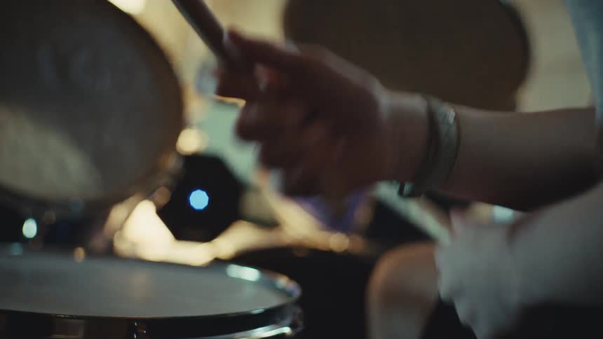 A close-up, out-of-focus shot of a drummer's hands playing a beat on a drum kit in slow motion