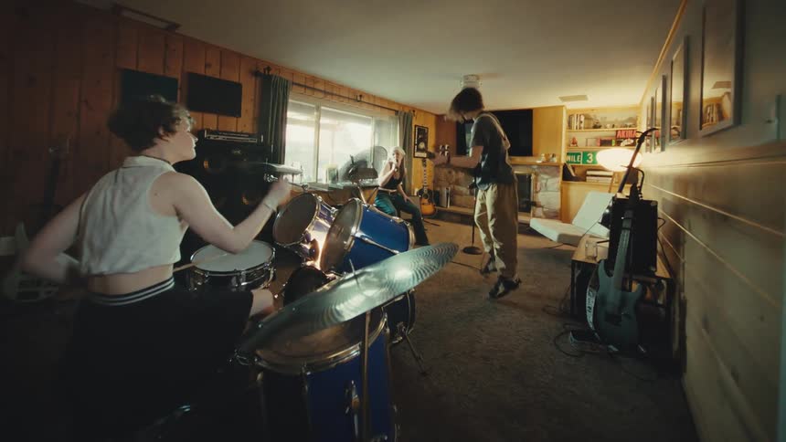 Dynamic and moving shot captures a young rock band energetically practicing in a home studio