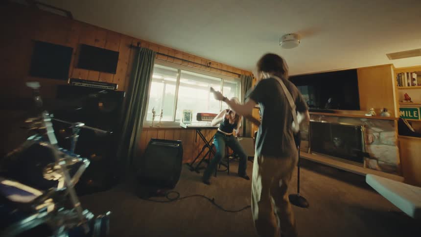 Dynamic and moving shot captures a young rock band energetically practicing in a home studio