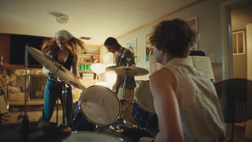A youthful rock band energetically jams together during a rehearsal in their home basement studio