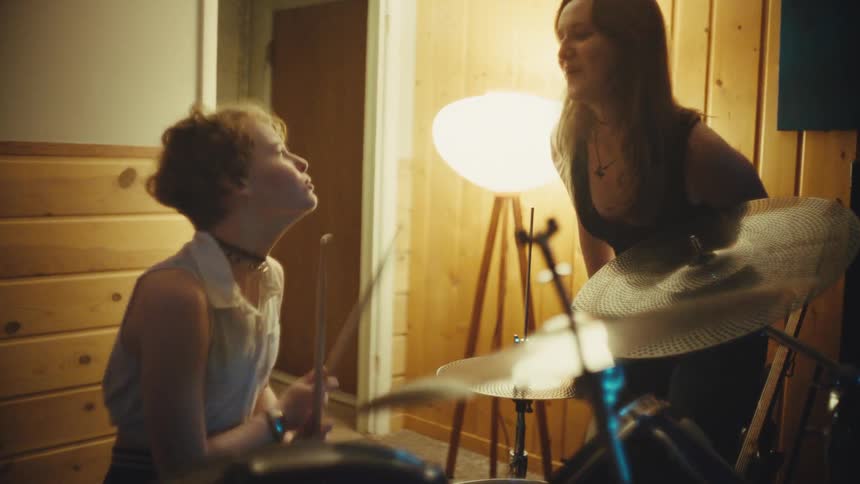 A female singer and drummer passionately sing together during an energetic band rehearsal in a music studio