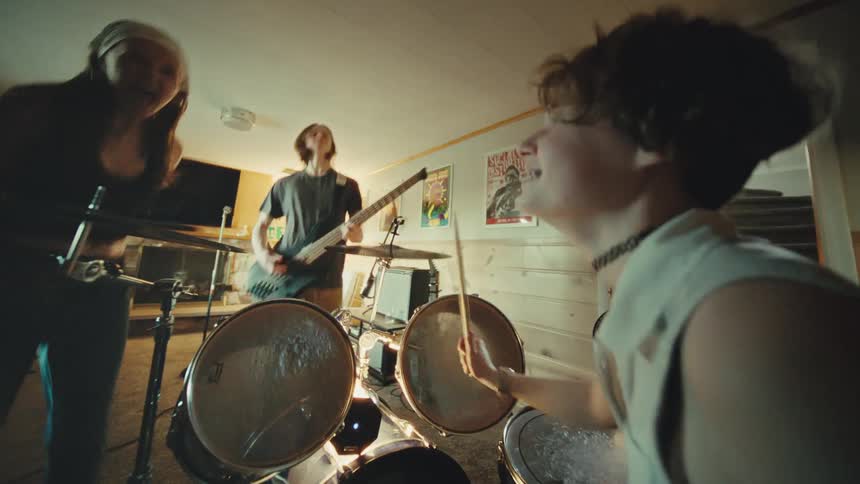 A youthful and energetic rock band passionately performs during a jam session in their home basement practice space