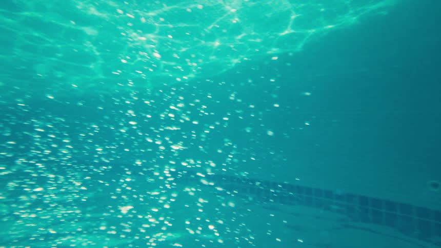 An ethereal underwater shot of sparkling bubbles rising through turquoise water illuminated by sunlight