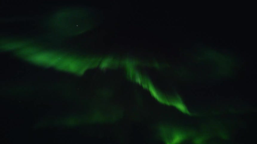 Awe-inspiring display of the vibrant green Aurora Borealis dancing across the dark night sky