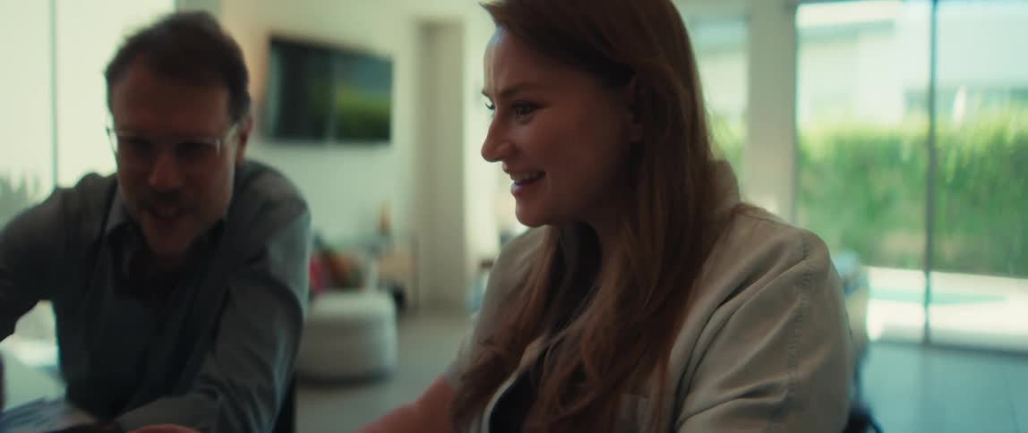 A woman collaborating with a male colleague on a laptop at home gets surprisingly good news and reacts with excitement
