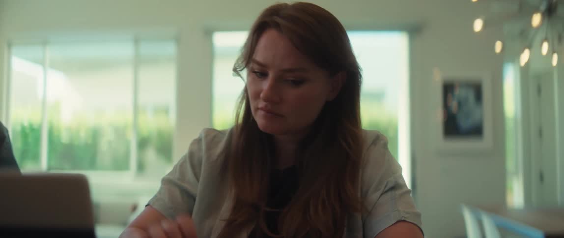 A worried couple uses a laptop and calculator to review their finances at home, showing signs of stress and concern