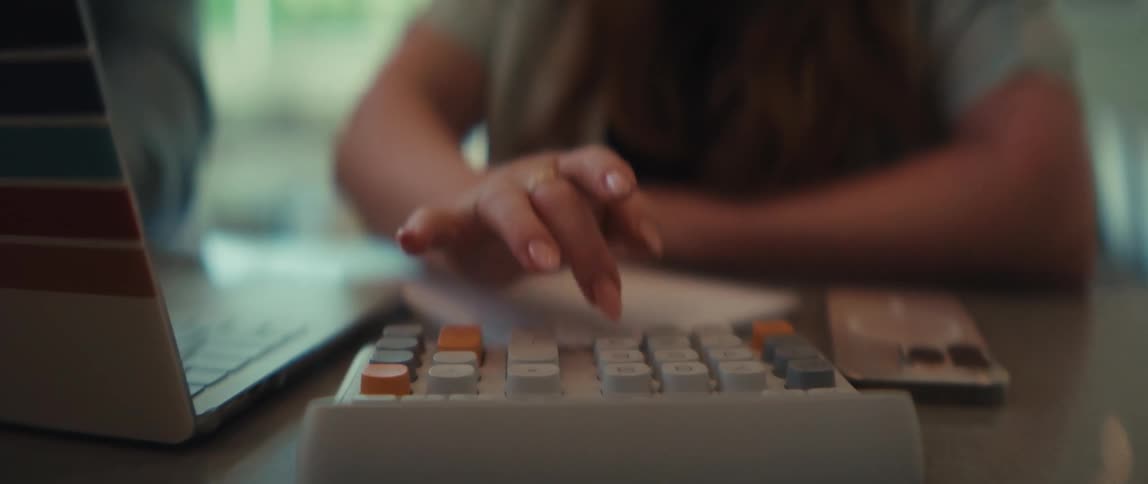 A man and woman review financial charts and use a calculator while working together in a modern office