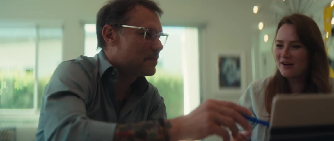 Two happy colleagues collaborate on a project using a laptop and celebrate their achievement with a handshake in a modern office