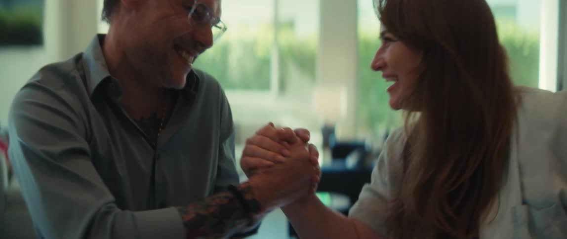 Excited business partners laugh and celebrate a new deal with a fun arm wrestling match in their office