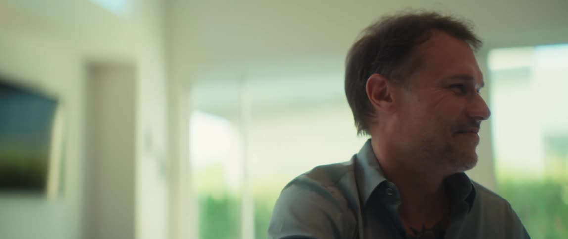 A happy businessman with tattoos removes his glasses and shakes hands with a colleague to finalize a deal in a modern office