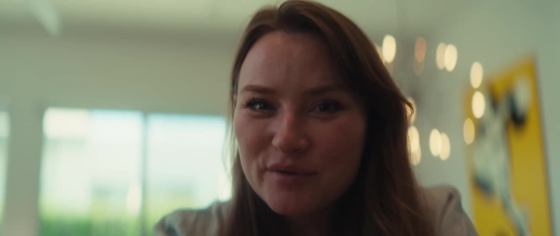 A close-up shot racks focus from a woman's hands to her smiling face as she engages in a friendly conversation