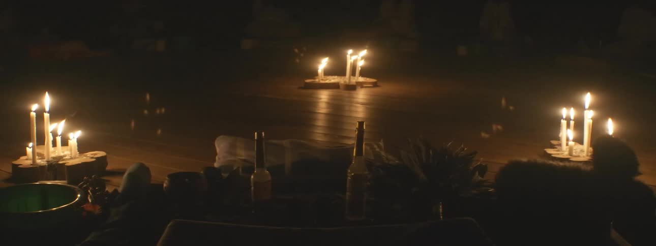 An altar is set up for a spiritual ceremony in a dark room lit by flickering candles