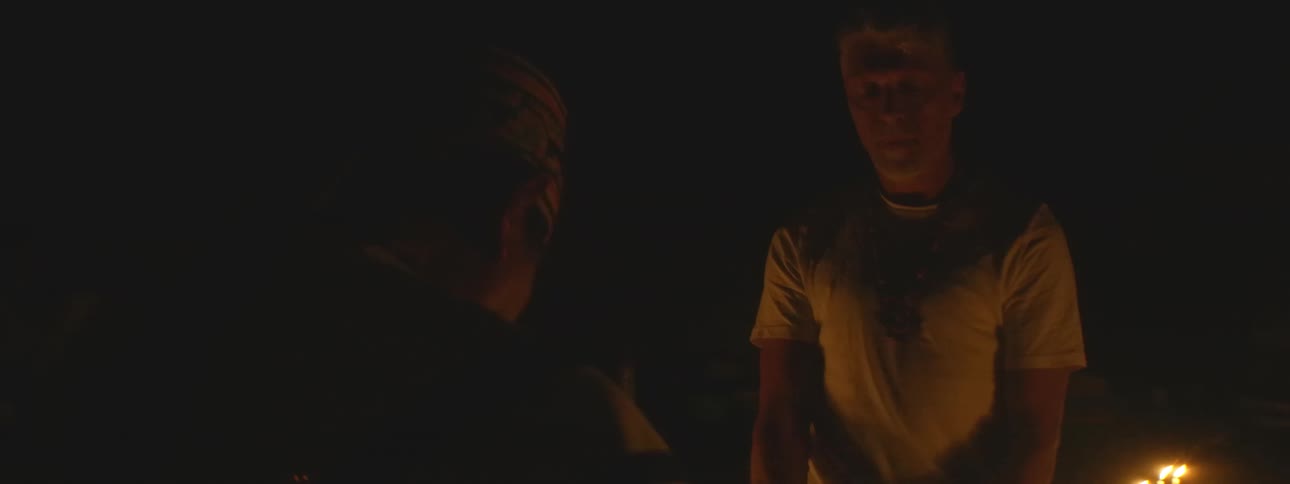 A man receives spiritual guidance from a shaman during an intense fire ceremony at night