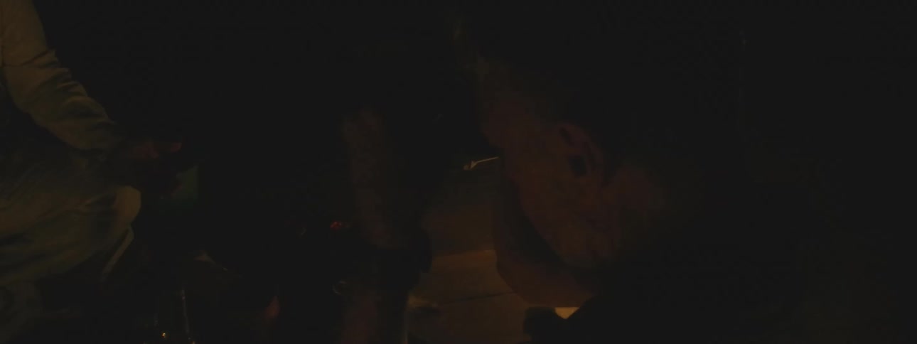 A shaman performs a spiritual healing ritual by candlelight for a participant in a dark, sacred space