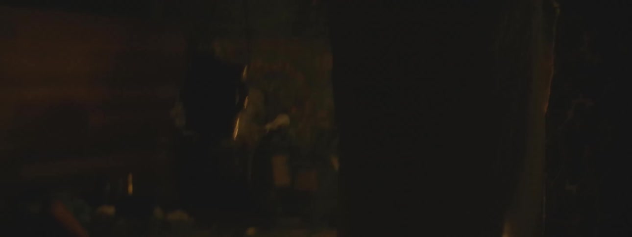 A shaman performs a spiritual healing ceremony, cleansing a person with smoke from a censer in a dark, candlelit room