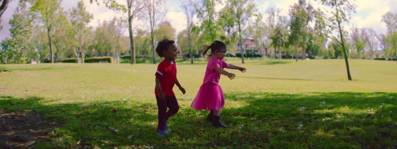 Joyful toddlers run and chase bubbles in a sunny park in a beautiful slow-motion shot
