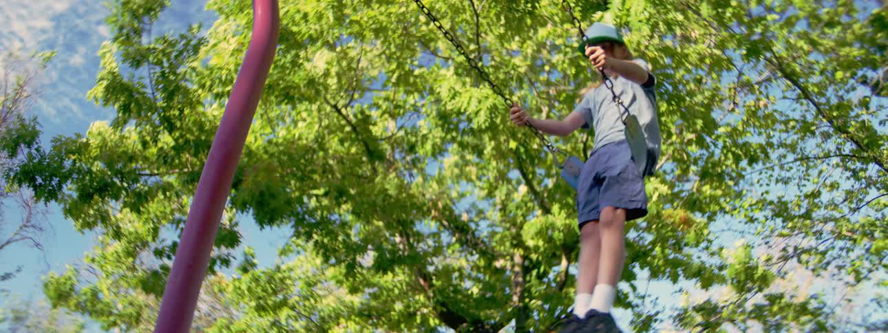 Low angle slow motion view of a carefree teenager swinging high on a swing set at the park on a sunny day
