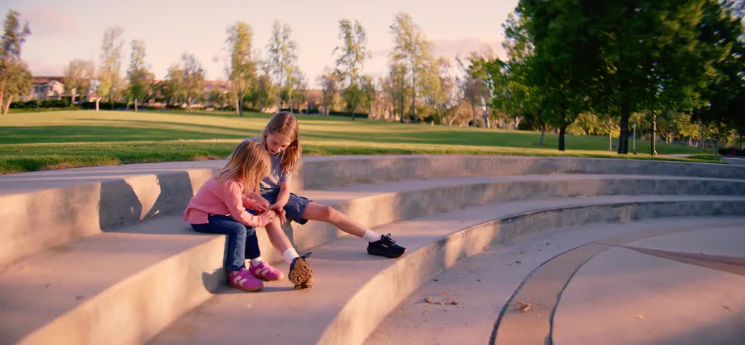 An older brother and his younger sister share a sweet moment and a hug on the steps of a park amphitheater