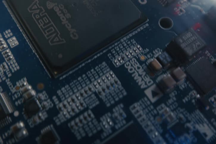 A detailed macro shot pans over a blue computer circuit board, revealing its intricate components and a glowing blue LED light