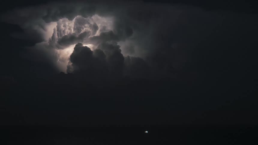 A dramatic thunderstorm lights up the night sky with powerful lightning flashes inside dark, rolling clouds