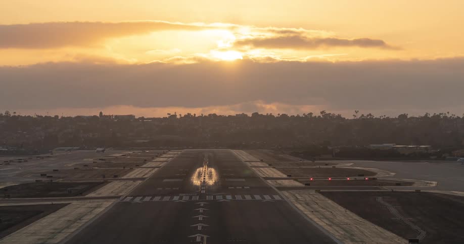 A stunning time-lapse captures airplanes landing and taking off on a busy runway against a brilliant golden sunset