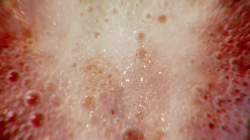 A psychedelic macro shot of a strawberry slice revealed amidst colorful, fizzy bubbles