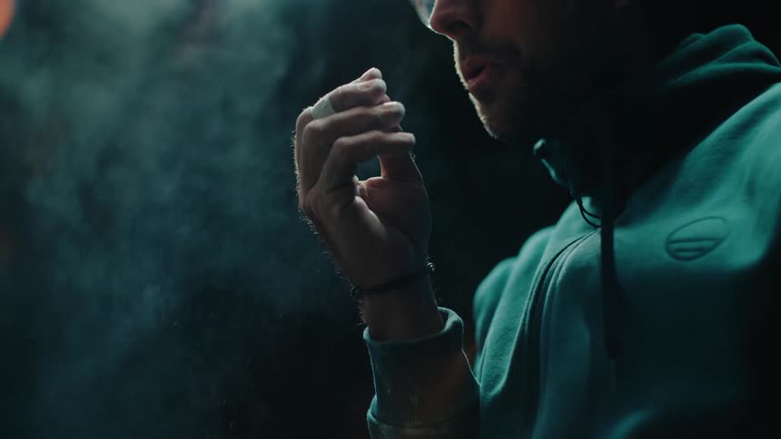 An athlete claps his chalked hands in slow motion, creating a dramatic cloud of dust before his workout