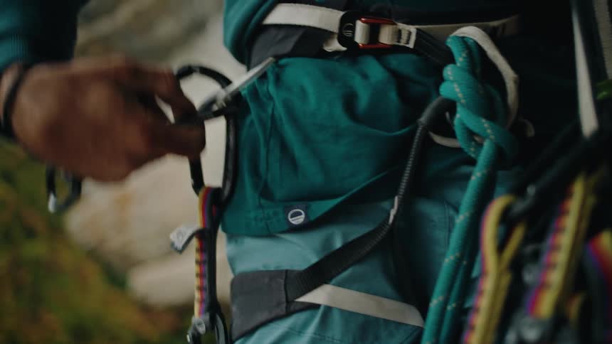 Detailed slow-motion shot of a climber methodically arranging quickdraws on their safety harness before an ascent