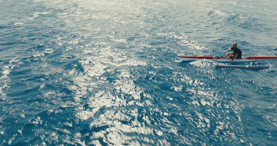 Aerial view of two men racing in outrigger canoes on the open ocean in slow motion