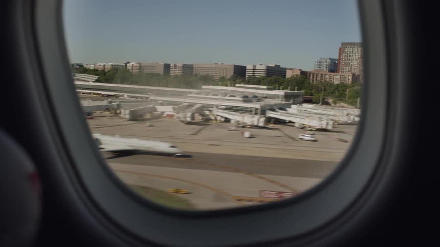A view from an airplane window showing the runway and terminal while taxiing, followed by the takeoff and an aerial view of the city