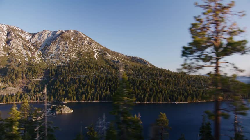 A scenic point-of-view drive along a winding road reveals the majestic, snow-capped mountains and serene blue waters of Lake Tahoe