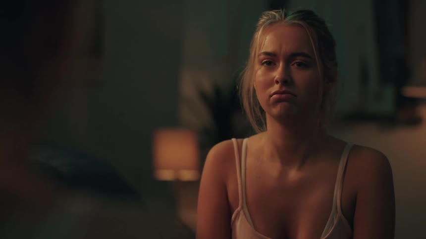 An insecure young woman anxiously examines a blemish on her face in the mirror at night