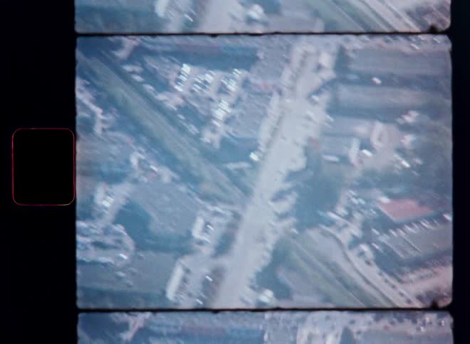 Vintage 16mm archival aerial footage captures a bustling cityscape with traffic on the streets below