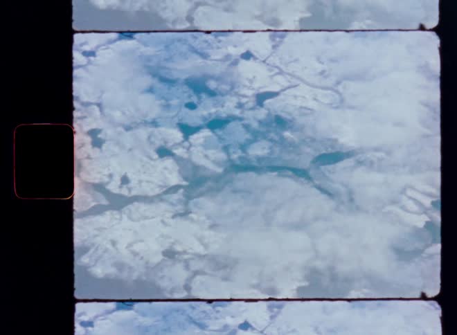 Vintage archival footage captures a view of the Earth's snow-covered, arctic landscape from space, ending with a colorful film burn effect