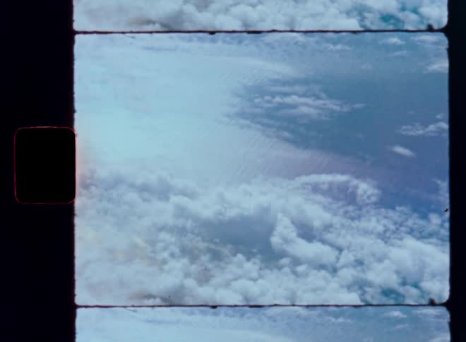 A vintage film strip captures a breathtaking aerial view of a vast sea of clouds from high above the Earth