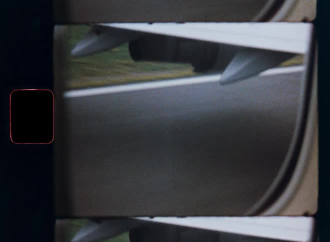 Vintage 8mm film captures the point-of-view from an airplane window as it speeds down the runway for takeoff