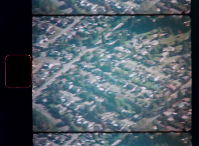 A slow aerial pan over a sprawling suburban neighborhood captured on authentic vintage 8mm film