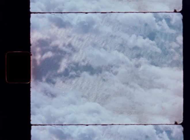 An aerial view from above a sea of fluffy white clouds, shot on vintage 8mm film