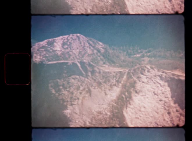 Vintage 8mm footage pans across a vast and rugged volcanic crater landscape under a clear sky