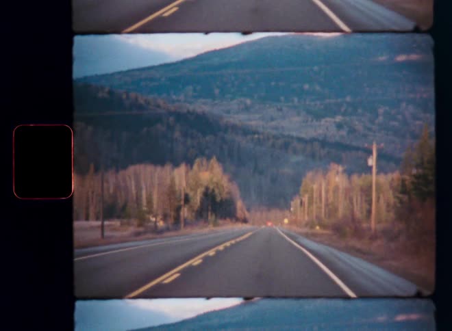 A vintage film strip shows a POV drive down a quiet country road towards forested mountains